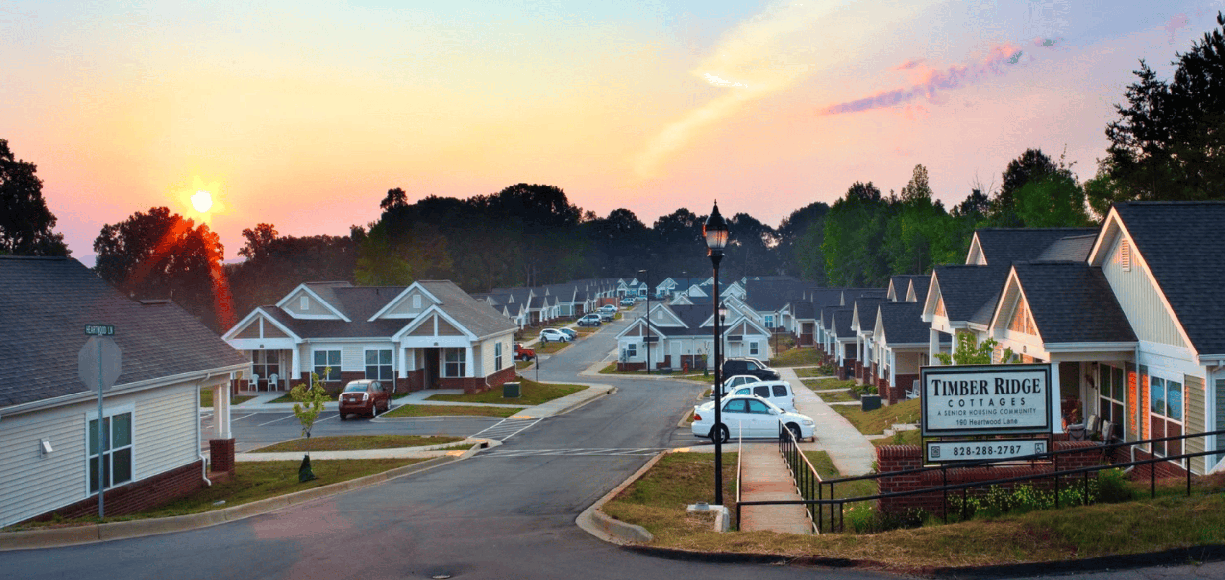 A sunset view of a residential street with a Timber Ridge Contractors sign.